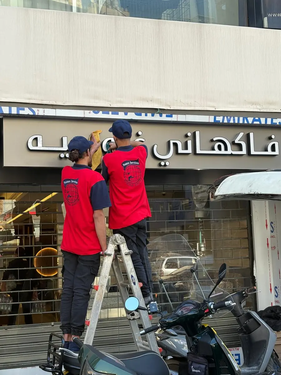 Cleaning a restaurant sign from a ladder